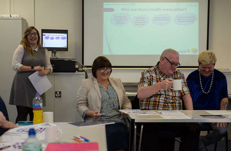 Two women and two men from the Health Team sit in front of a presentation they are delivering to a group of health professionals