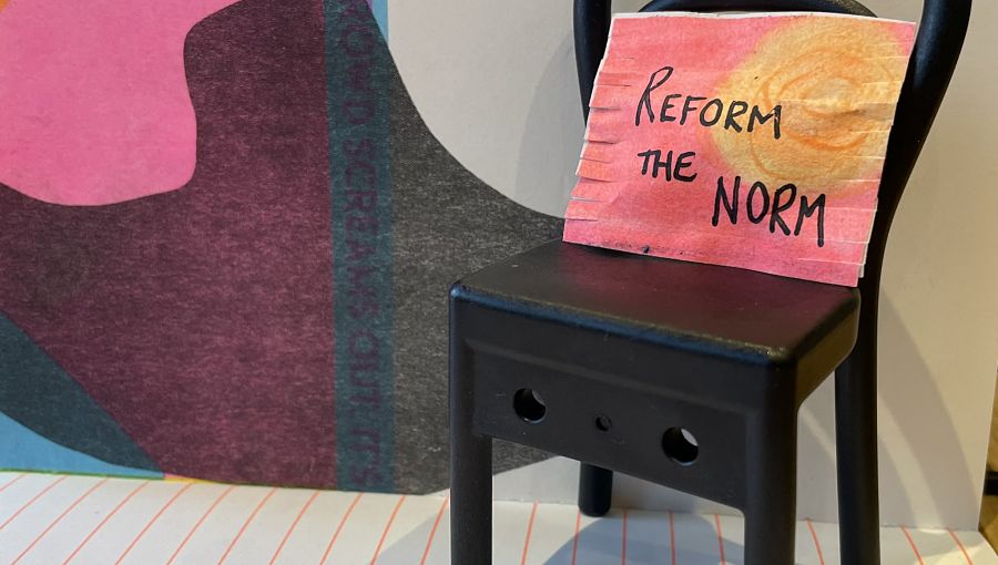 A black chair has the colourful Reform the Norm on its seat