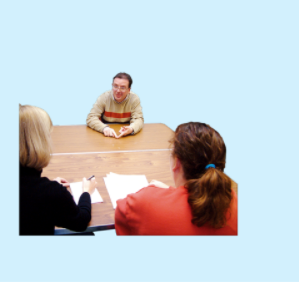 Three people sit around a table talking